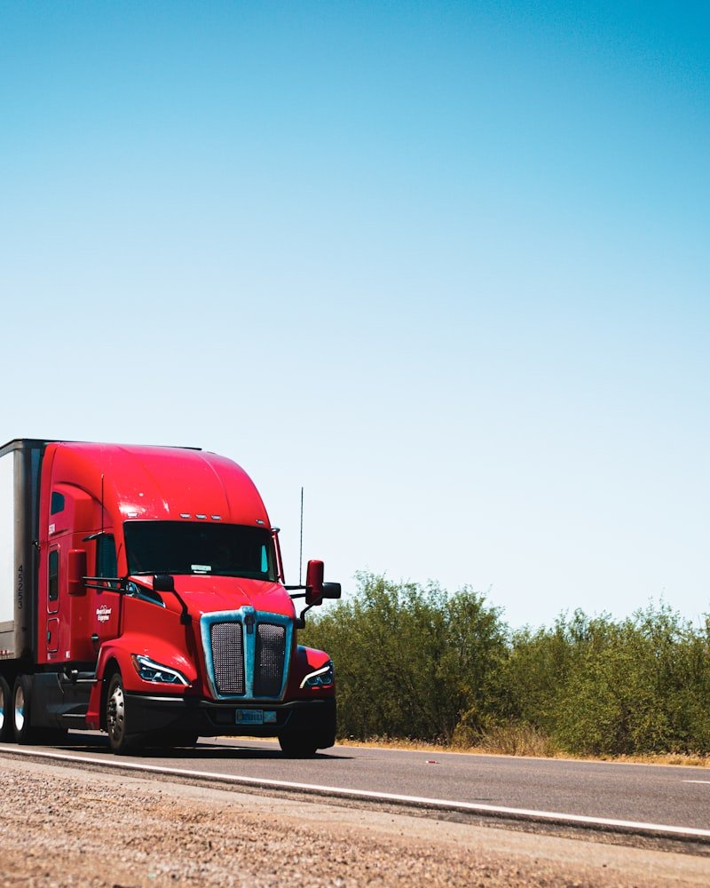 Red Canadian commercial semi truck on a country highway, representing fleet operations