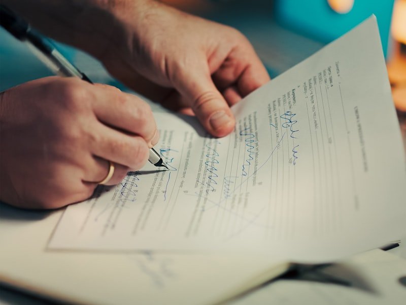 Close-up of hands signing a commercial vehicle sale and lease agreement document