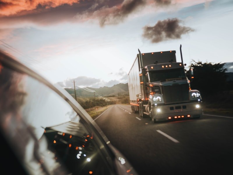 Commercial semi truck with headlights on approaching at dusk — safe night operations
